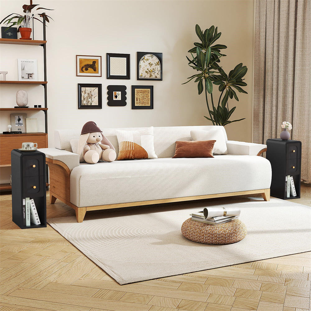 A modern white fabric daybed with light wood legs, styled in a warm, contemporary living room setting with decorative pillows, a plush toy, side tables, framed wall art, and a large potted plant.
