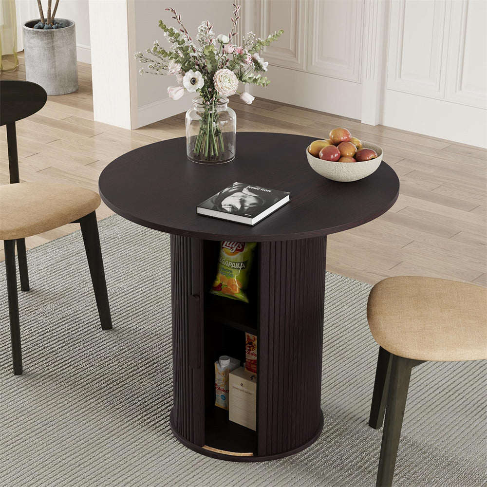 Round dark wood table with storage shelves, flowers, and fruit in a room setting.
