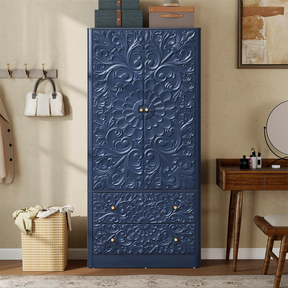 A tall navy blue storage cabinet with ornate embossed floral scrollwork on the doors and drawers, shown in a styled room setting with a wooden desk, mirror, and wall decor.
