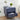 Decorative blue nightstand with embossed patterns, lamp, and plant in a room setting.