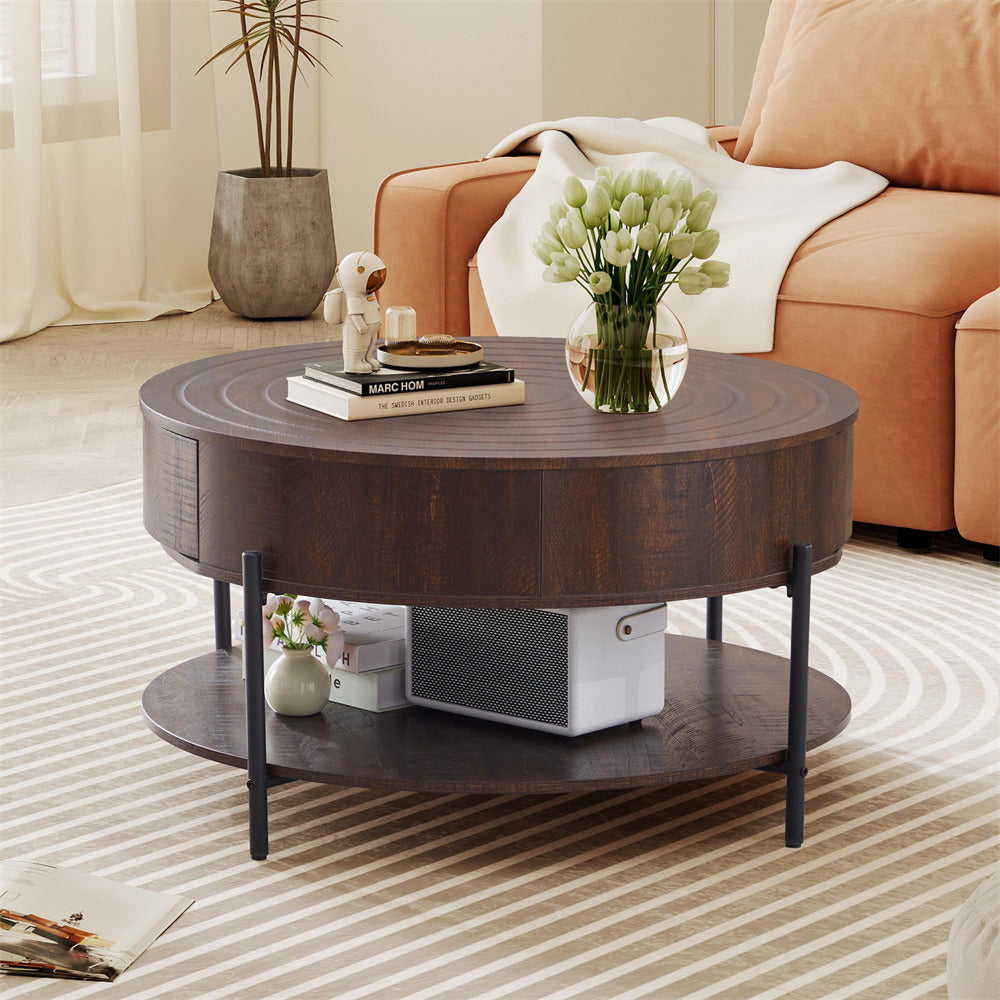 Round wooden coffee table in a living room setting with books, a vase, and decorative items.