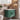 Bathroom vanity with green cabinet and white countertop, featuring modern floating design and durable MDF finish.