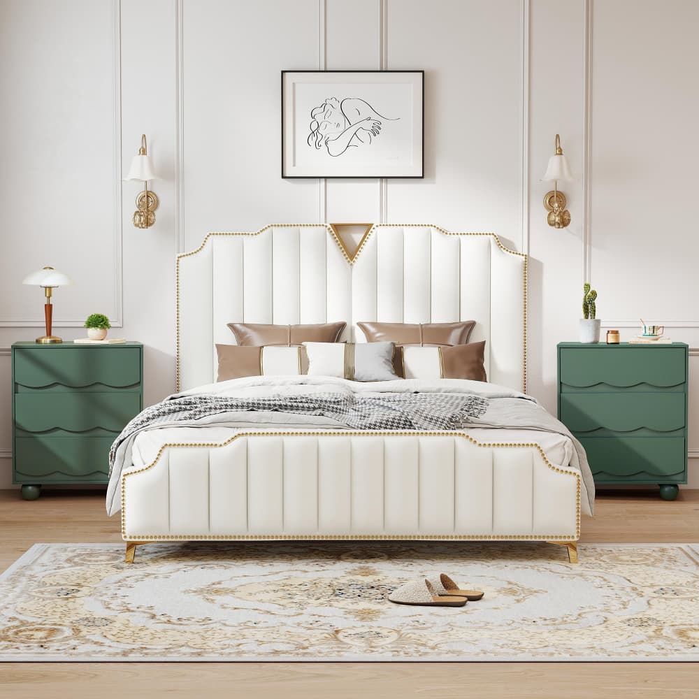 A luxury upholstered bed with a tall, vertically channeled headboard and gold nailhead trim, styled in a symmetrical bedroom setting with green nightstands, gold wall sconces, and a patterned rug.