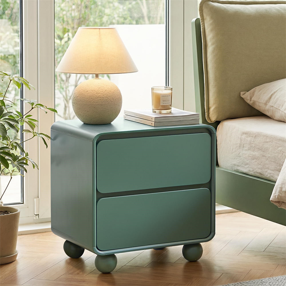 Green nightstand with lamp and candle next to a bed in a bedroom