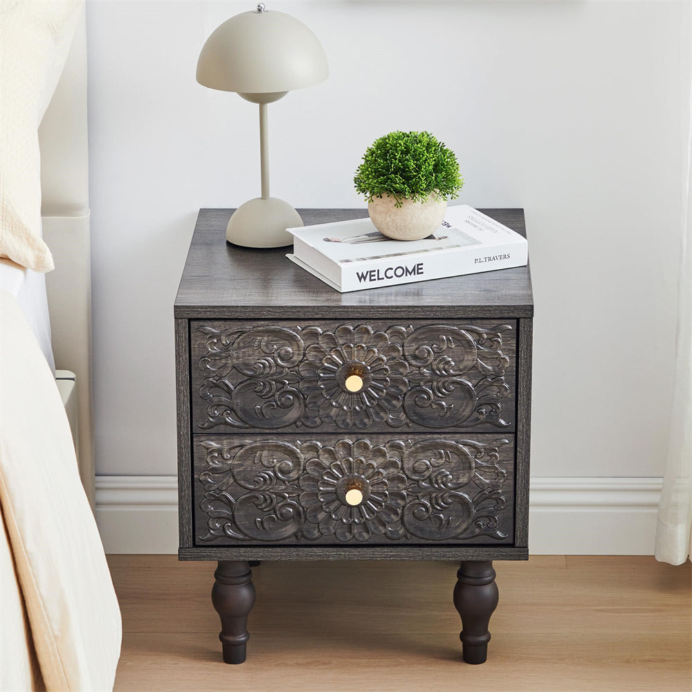 Decorative grey nightstand with floral patterns, lamp, and books in a bedroom setting.
