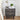 Decorative grey nightstand with floral patterns, lamp, and books in a bedroom setting.