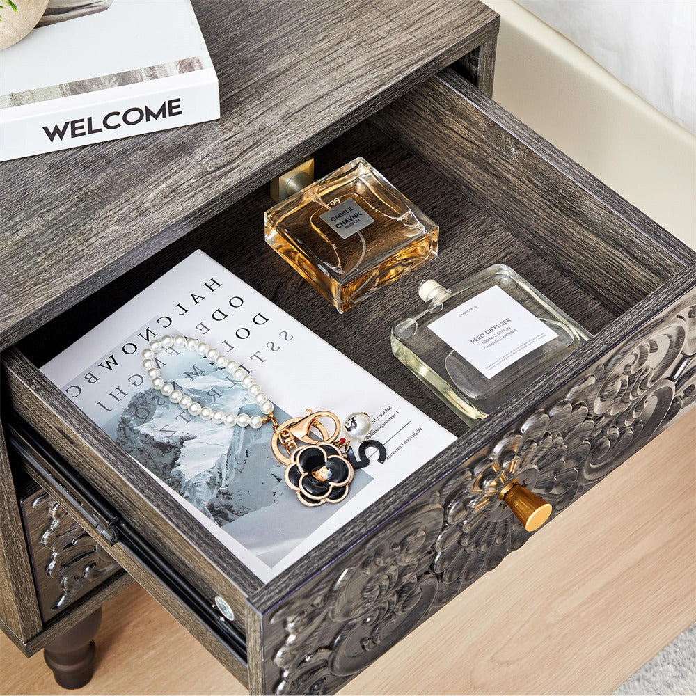 Decorative grey wooden drawer with jewelry and perfume bottles on a wooden surface.