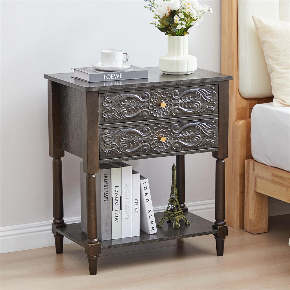 Decorative grey nightstand with embossed design, books, and a vase in a bedroom setting.