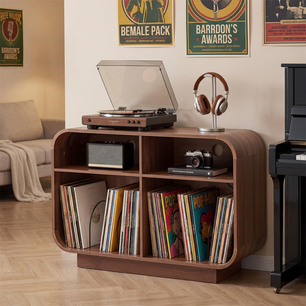 A wooden record player console with open shelves holding vinyl records, a turntable on top, and headphones on a stand, set in a living room with posters on the wall.