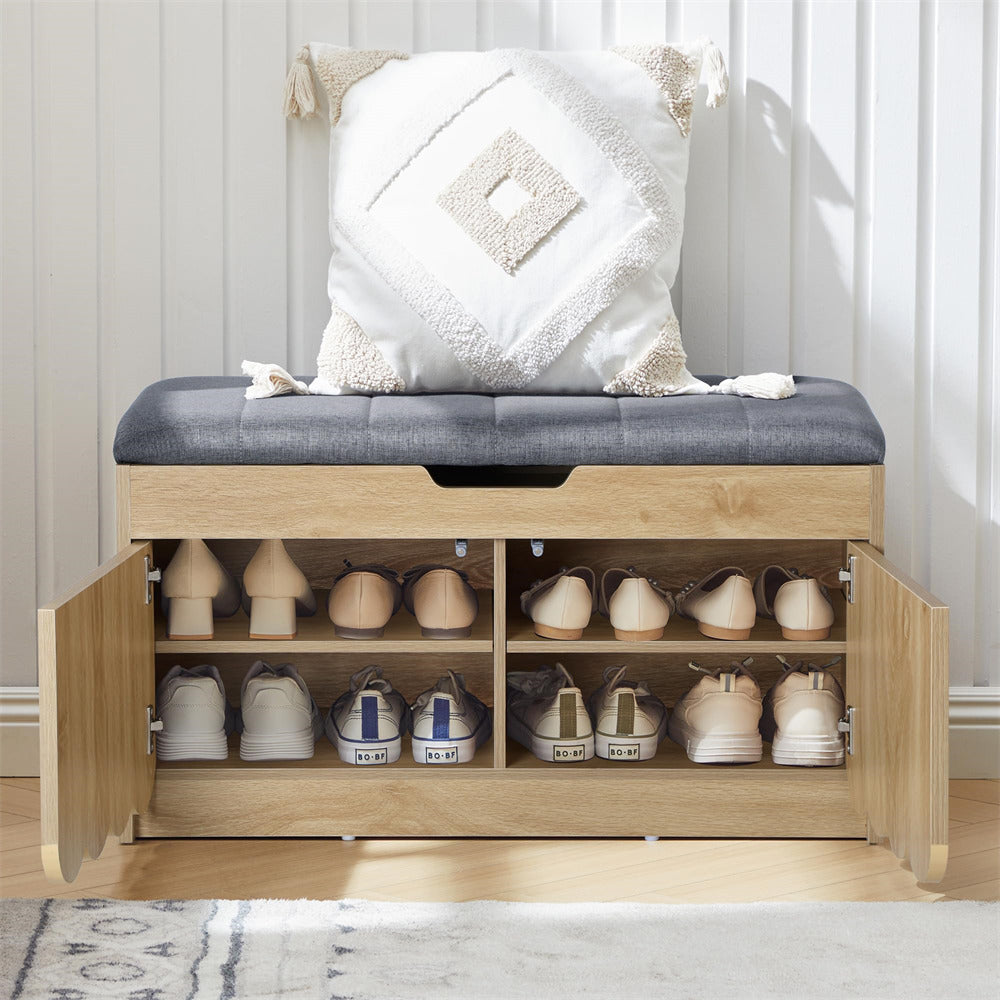 Wooden shoe storage bench with open doors revealing shoes on a wooden floor.