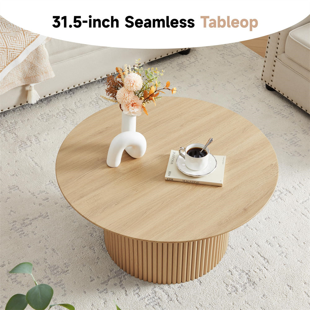 Round wooden coffee table with a vase of flowers and a cup on a light-colored floor.
