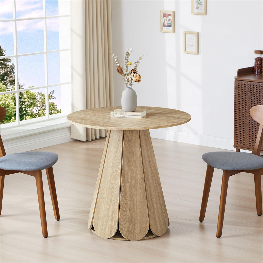 Round wooden table with decorative items in a bright room with large windows.