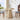 Round wooden table with decorative items in a bright room with large windows.