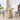 Round wooden table with decorative items in a bright room with large windows.