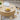 Round wooden coffee table with a laptop, cup, and plate of bread in a living room setting.