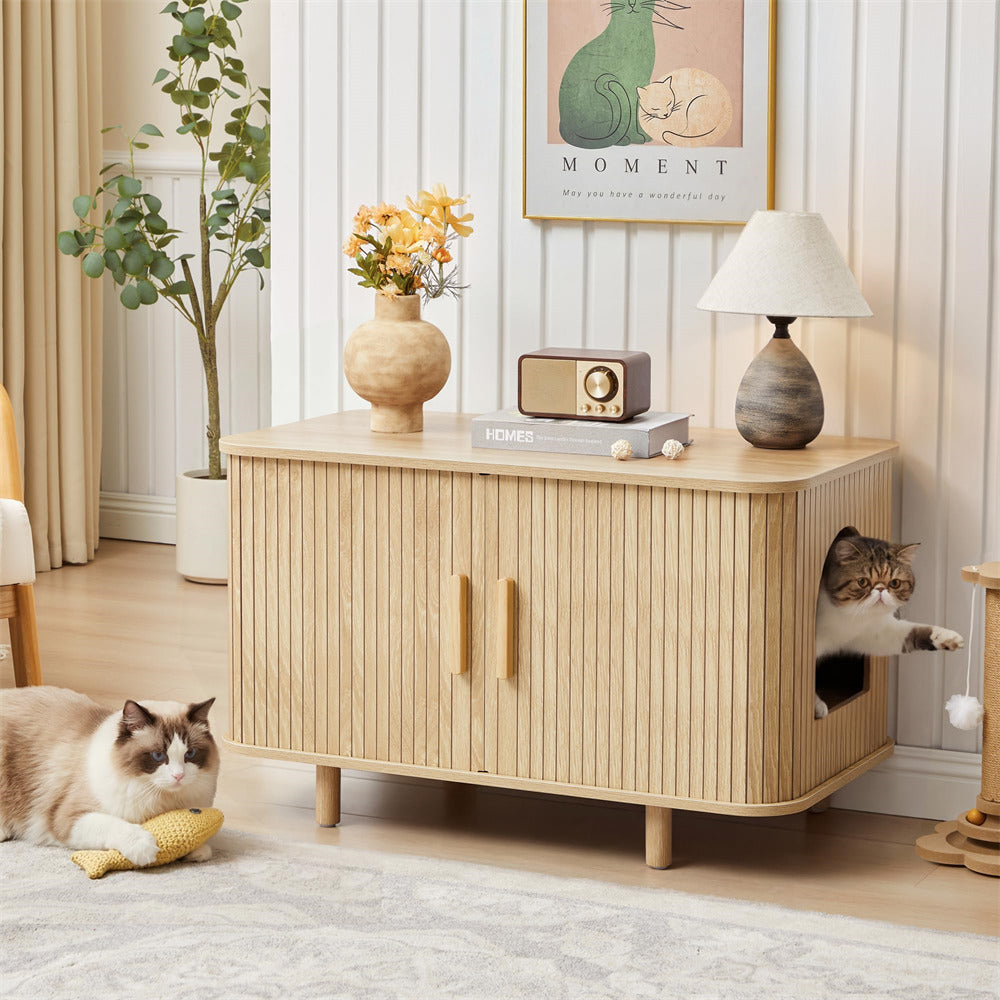 Wooden cat litter box with a cat peeking out, another cat playing with a toy nearby, in a cozy room setting.