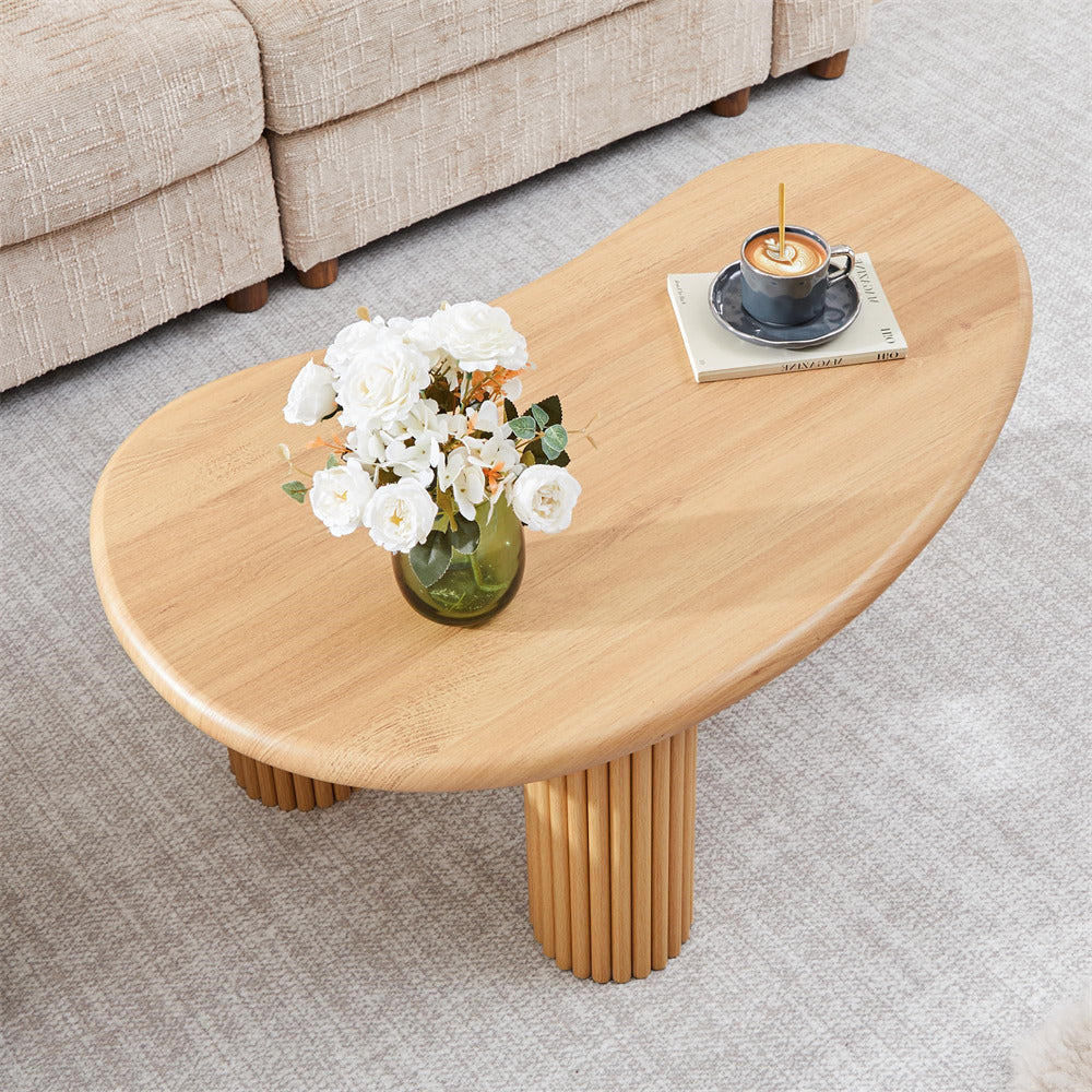 Wooden coffee table with a vase of flowers and a cup on a gray carpeted floor.