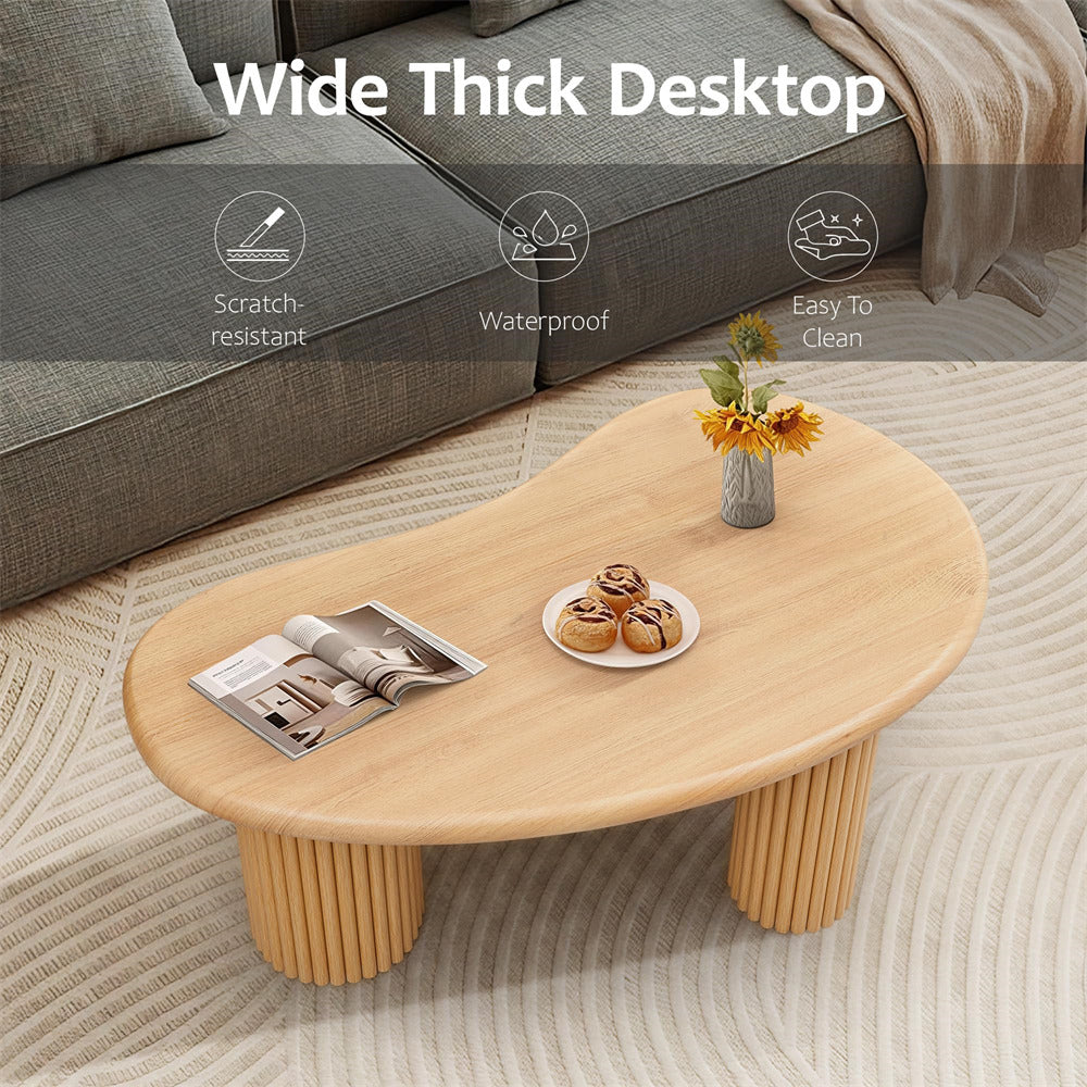 Wooden coffee table with a magazine, plate of cookies, and vase of flowers in a living room setting.
