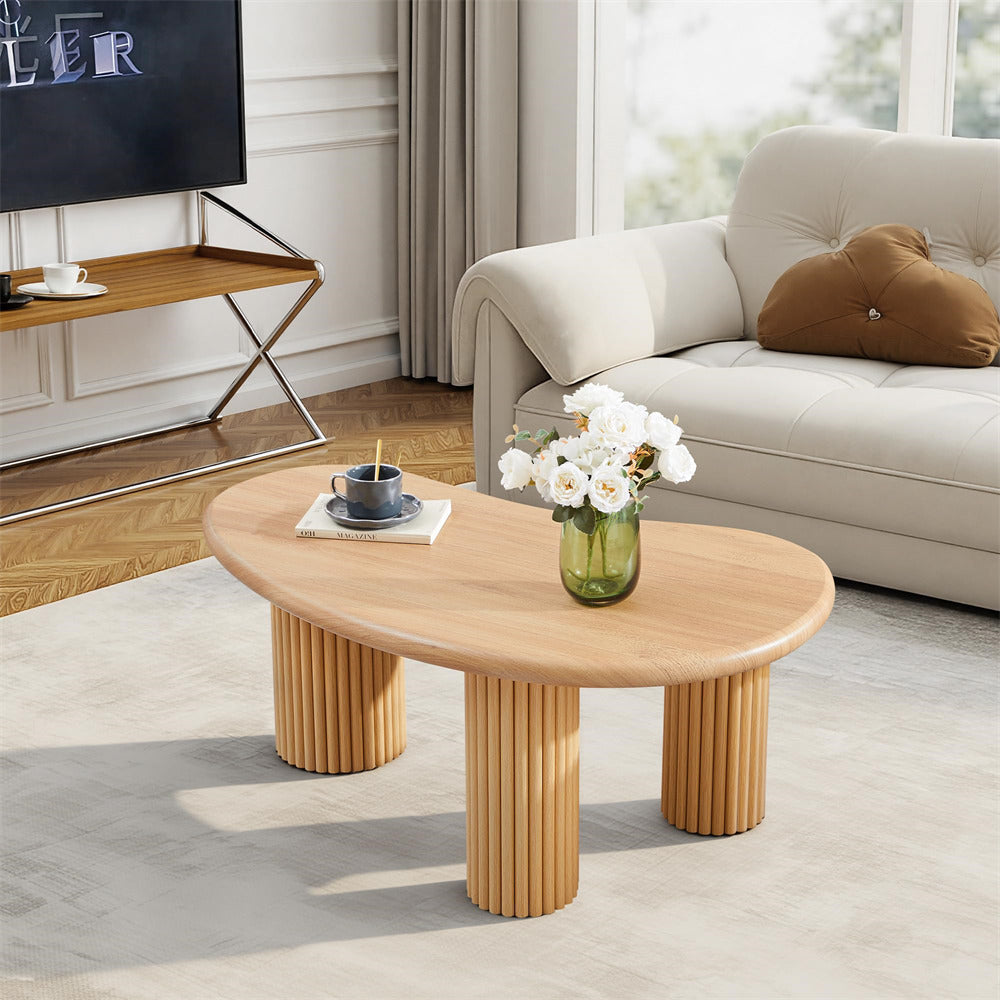 Wooden coffee table in a living room with a vase of flowers and a candle.