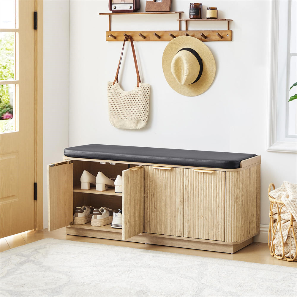 Wooden shoe bench with storage compartments, cushioned seat, and shoes inside, with a hat and bag hanging above.