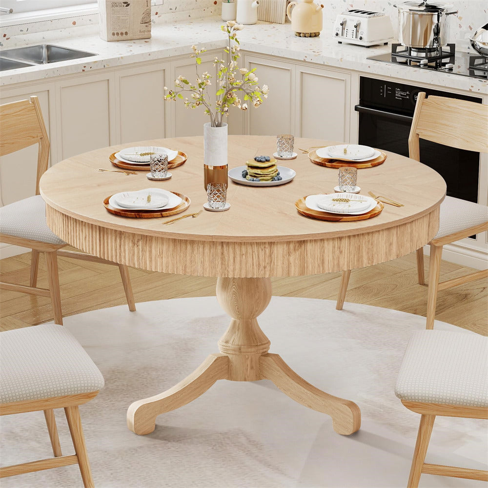 Round wooden dining table set in a kitchen with chairs and plates.