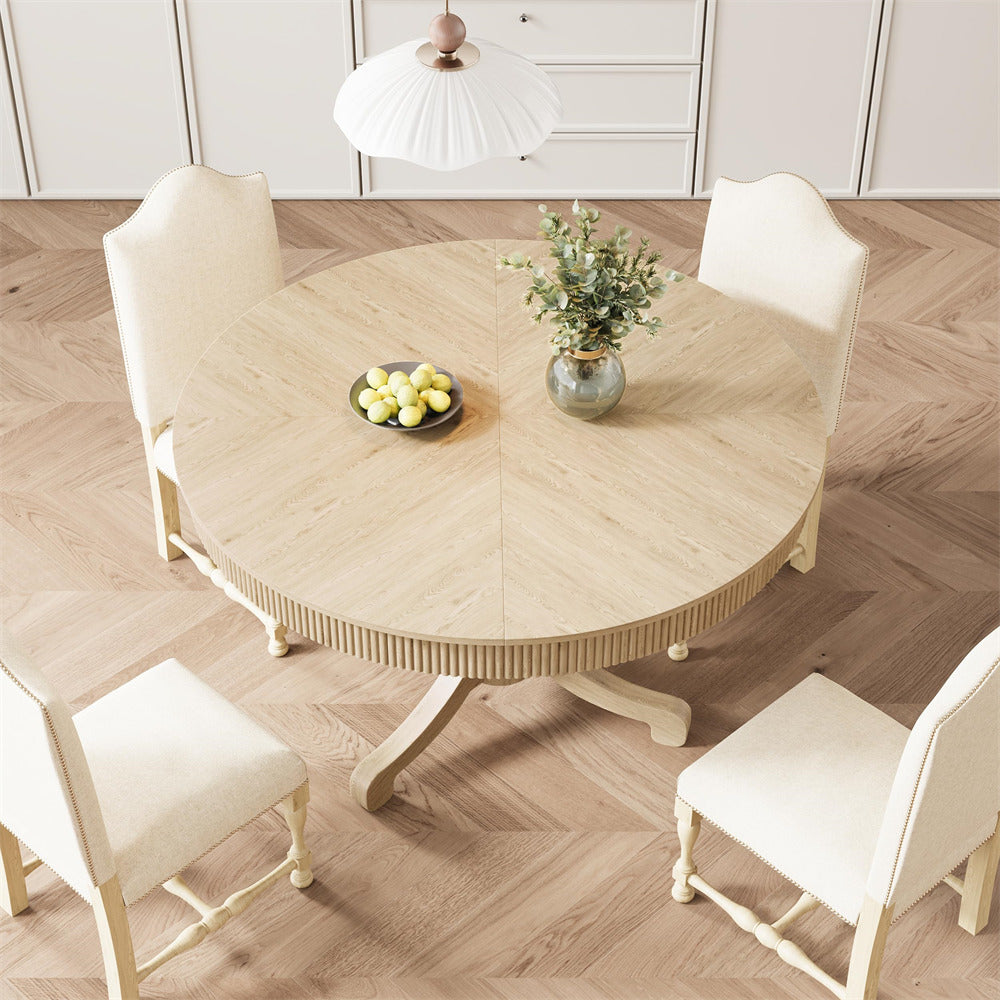 Round wooden dining table with four chairs on a wooden floor.