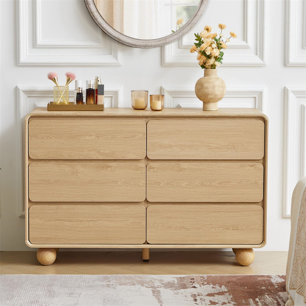 Wooden dresser with decorative items in a room with white walls and a mirror.