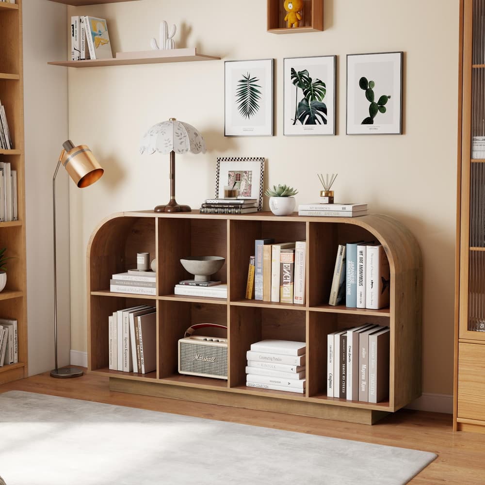 A wooden arched bookcase with nine cubbies, styled with books, a lamp, a small plant, and decorative items in a warm, modern room setting.