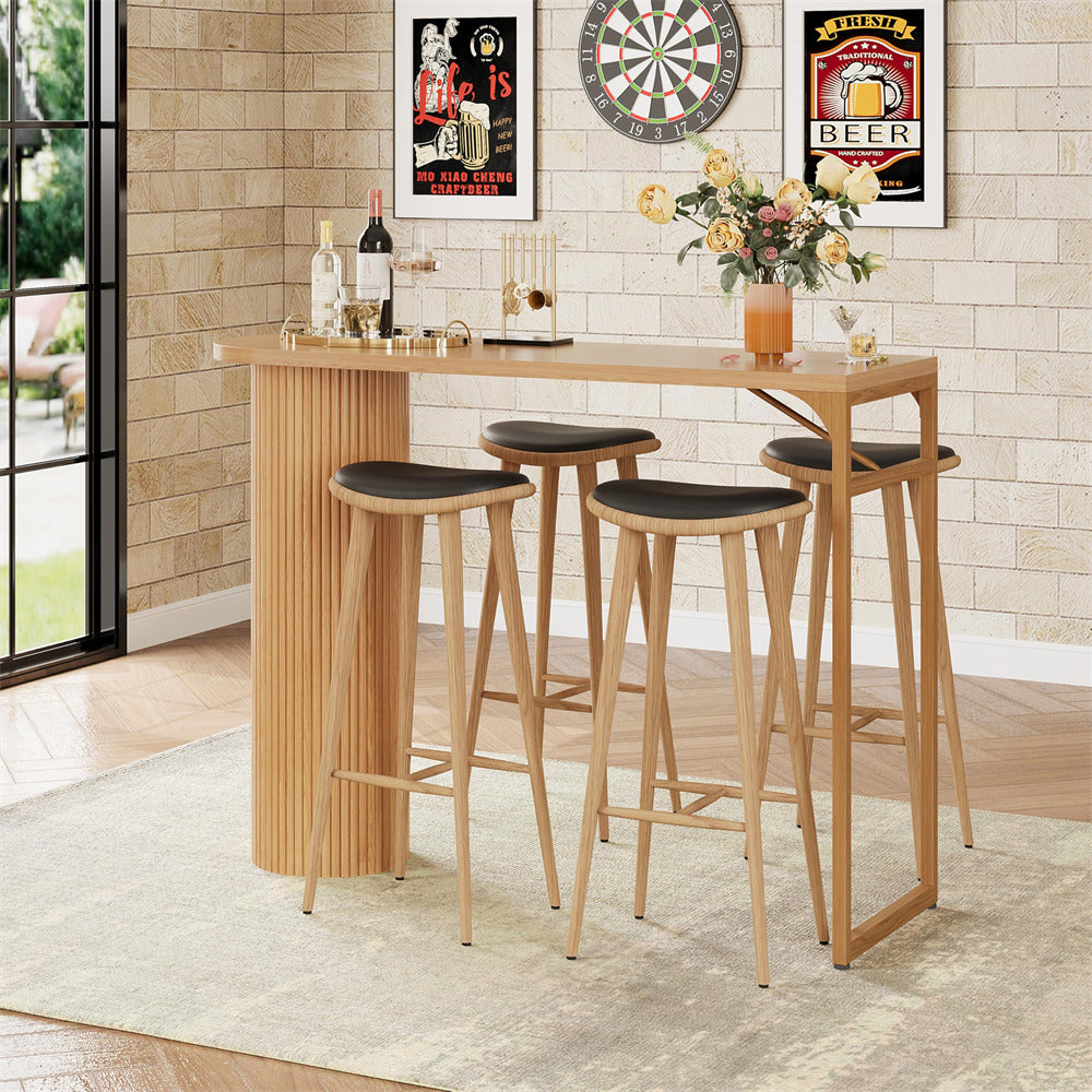 Wooden bar table with four stools in a room with a dartboard and beer posters on the wall.