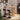 Wooden bar table with two stools against a white brick wall.