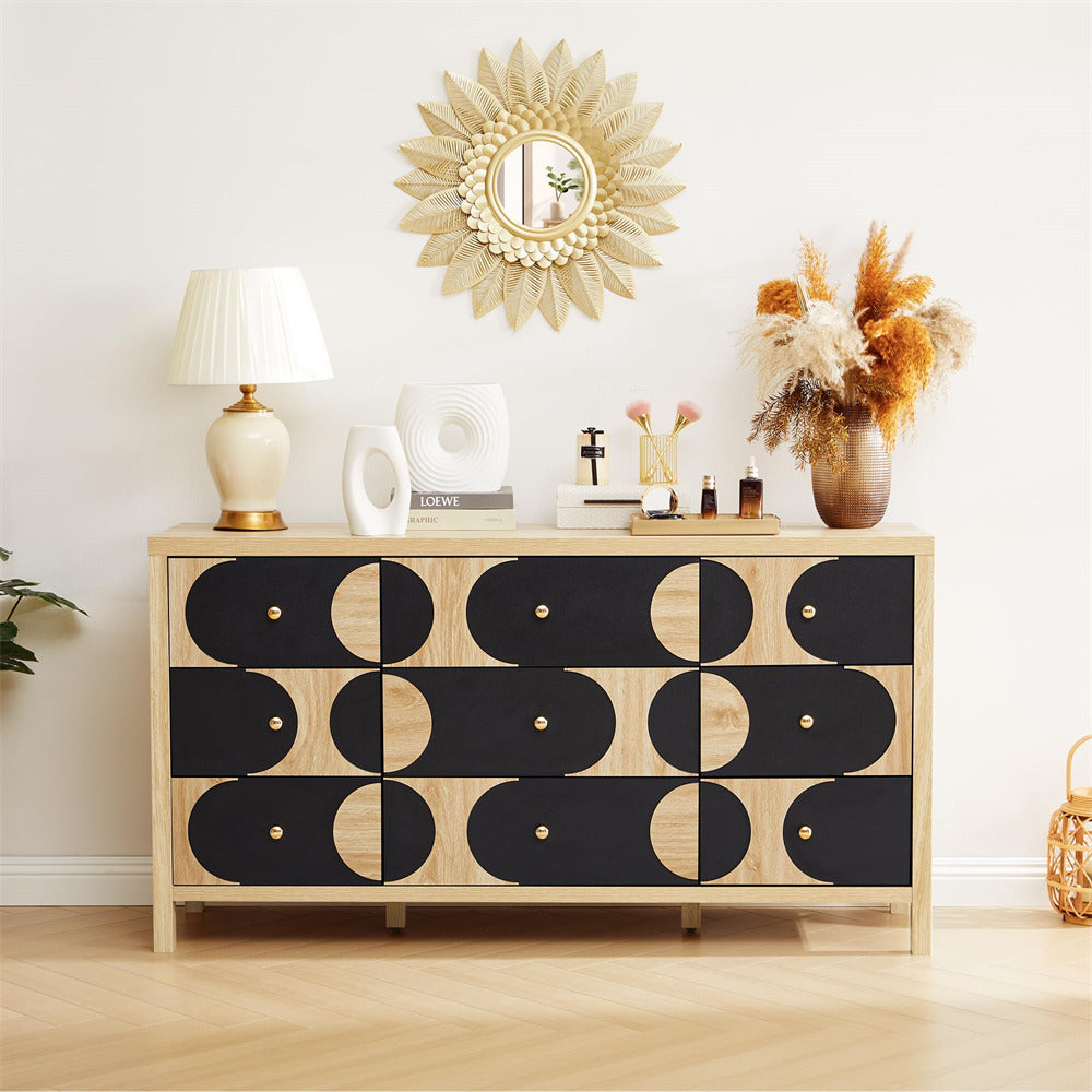 Wooden dresser with black geometric pattern, decorative mirror, lamp, and flowers in a room.