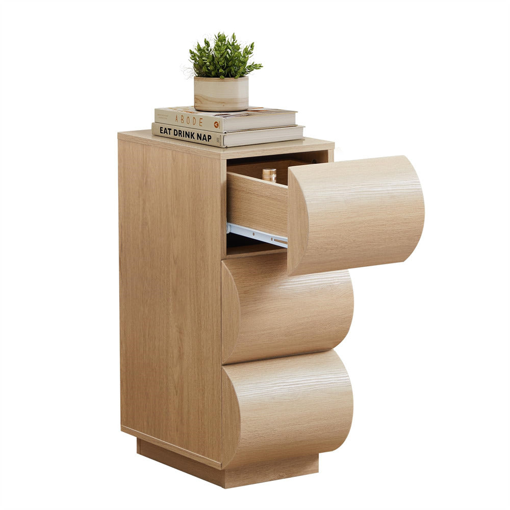 Wooden side table with curved design and open drawer, topped with books and a plant.