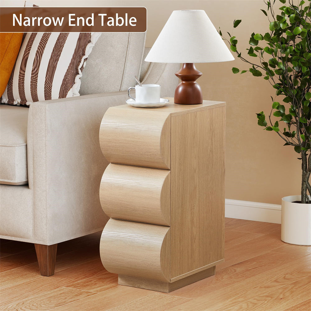 Narrow wooden end table with lamp and cup next to a beige sofa in a living room.