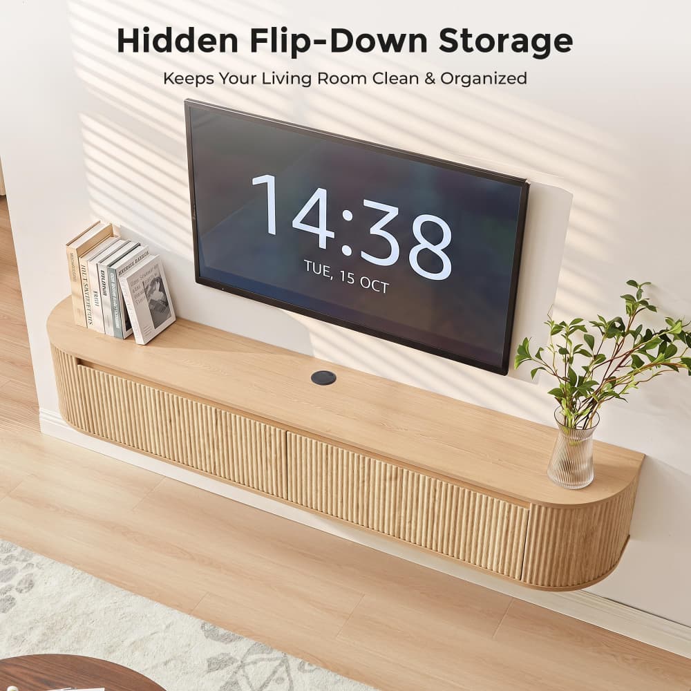 A floating light wood TV stand with a ribbed front and curved bottom edge, shown mounted against a white wall in a styled living room. A black TV, books, a small vase with greenery, and text reading 'Hidden Flip-Down Storage Keeps Your Living Room Clean & Organized' are visible.