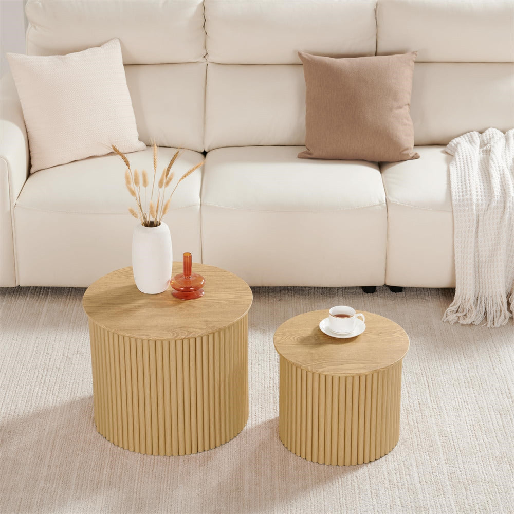 Two wooden coffee tables in front of a beige sofa with decorative items on top.