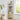 Beige corner shelf with decorative items in a room with a window and plant.