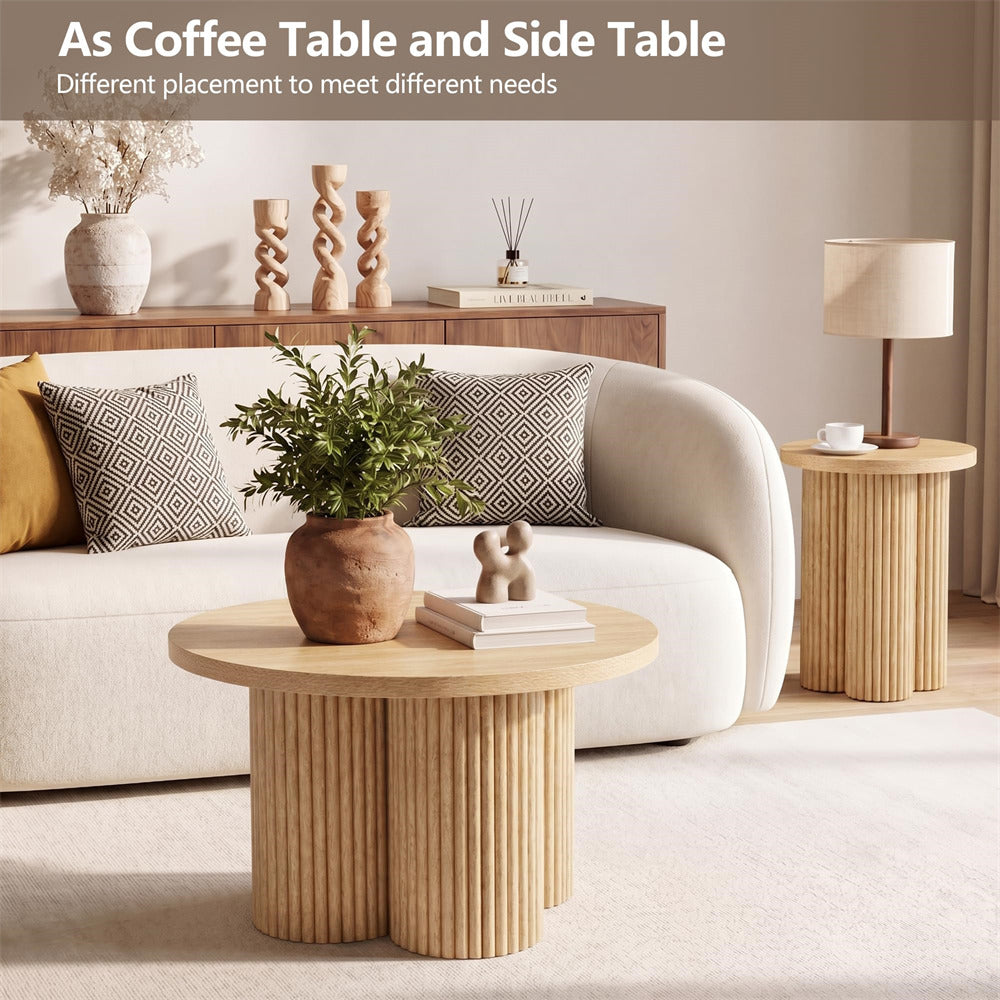 A styled living room scene showing two ribbed wood coffee and side tables in a modern interior. A cream sofa, patterned pillows, a lamp, books, and decorative plants are visible.