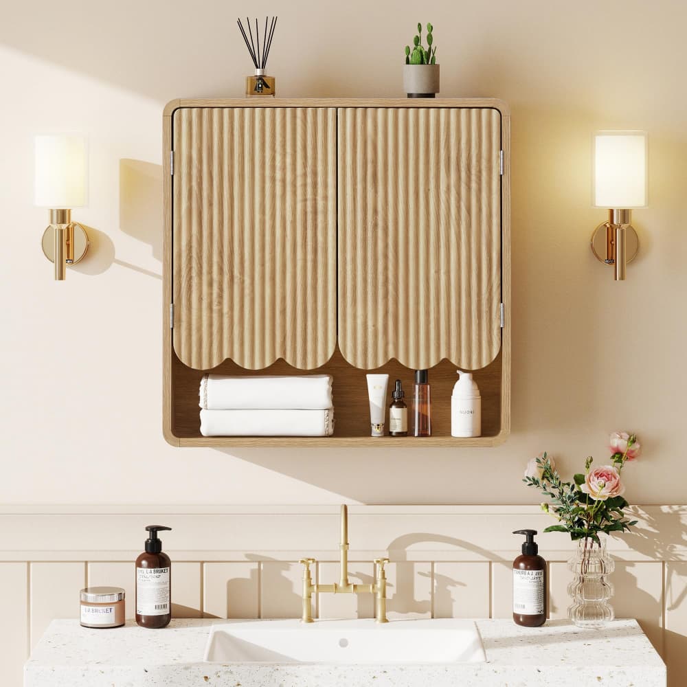 A wall-mounted wooden bathroom medicine cabinet with vertically pleated doors, styled above a sink with toiletries, flanked by two wall sconces.