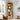 Wooden bookshelf in a living room with decor items and a window in the background