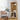 Wooden bookshelf with decorative items in a room with a table and chairs.