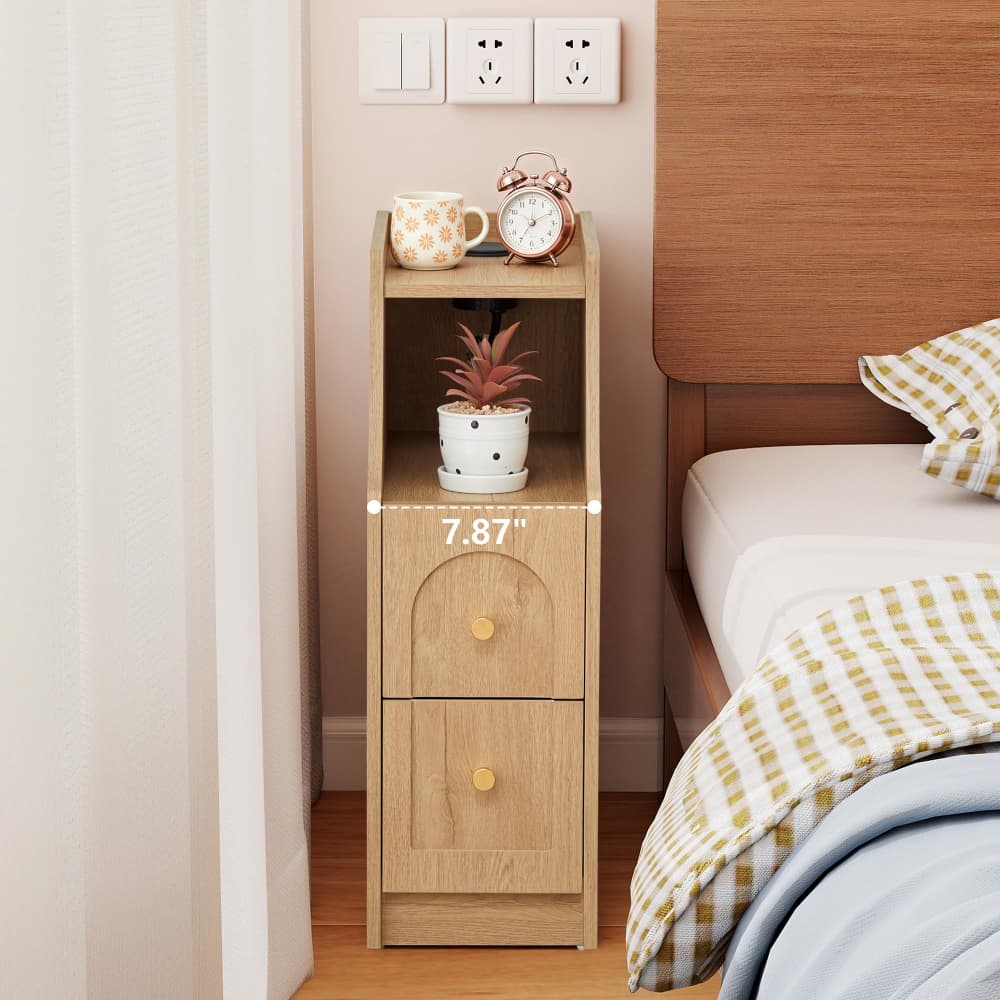 A light oak wood nightstand with two drawers and an open shelf, shown in a bedroom next to a bed. White dimension text overlay reads '7.