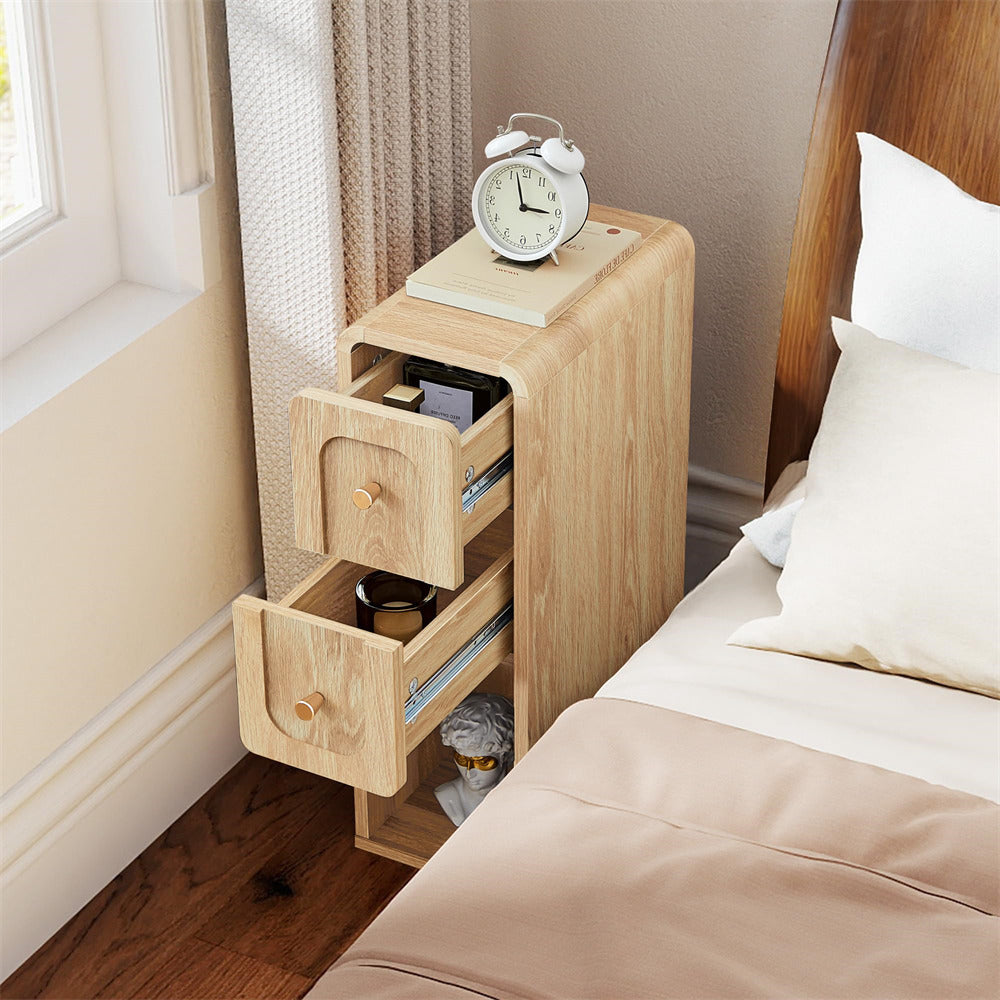 Wooden nightstand with open drawer next to a bed with pillows and bedding.
