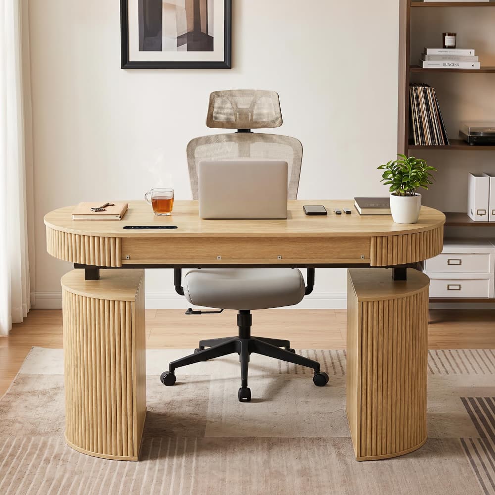 A modern curved wooden desk with ribbed cylindrical legs and a matching mesh office chair, styled in a bright home office setting with a laptop, plant, and books.