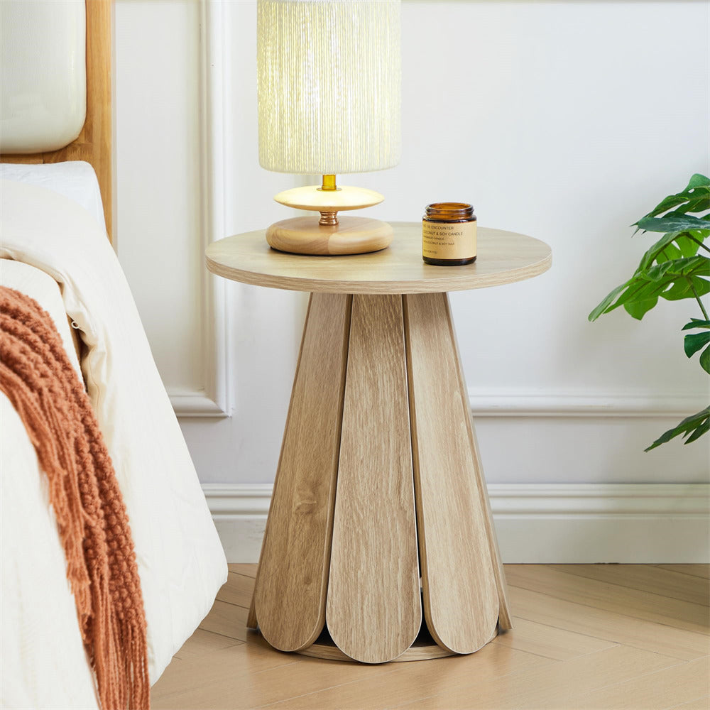 Wooden side table with lamp and candle next to a bed in a bedroom setting