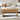 Wooden coffee table with a laptop and small items in a living room setting.