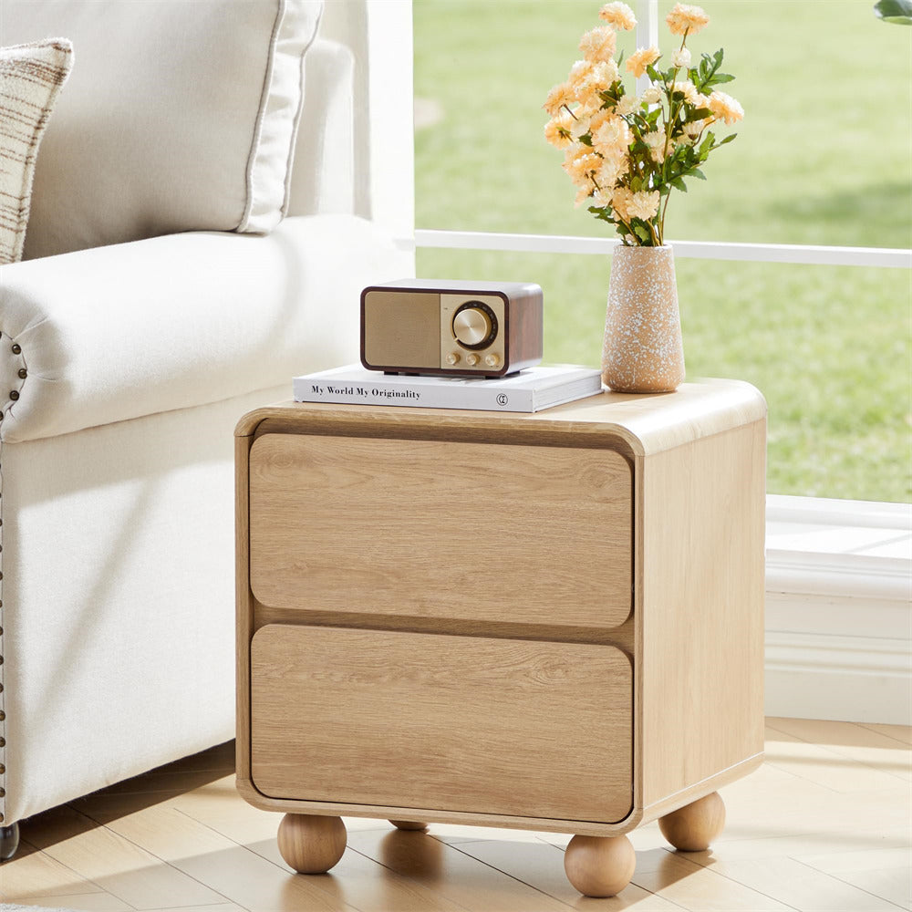 Wooden side table with a radio and vase of flowers next to a sofa in a living room.