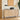 Wooden sideboard with decorative items in a room with a painting and plant.