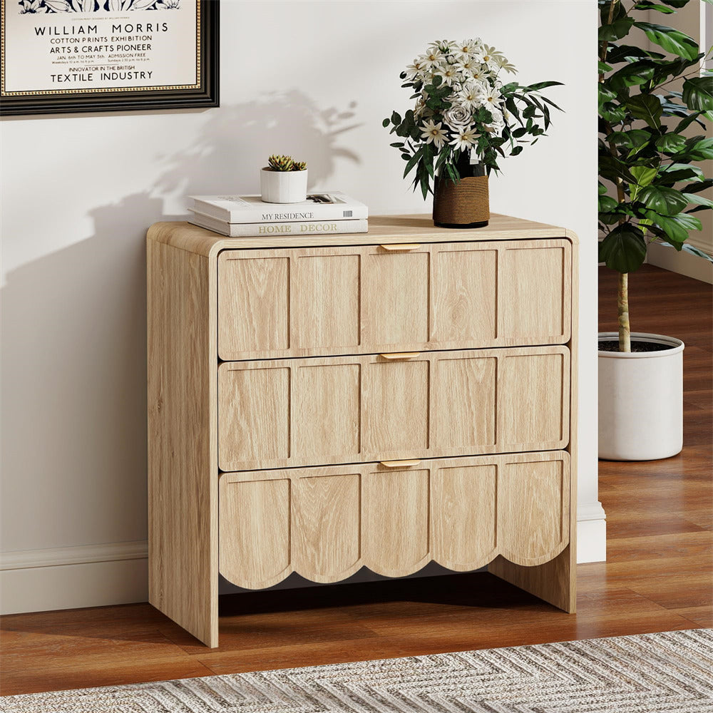 Wooden dresser with three drawers in a room with a plant and framed picture on the wall.