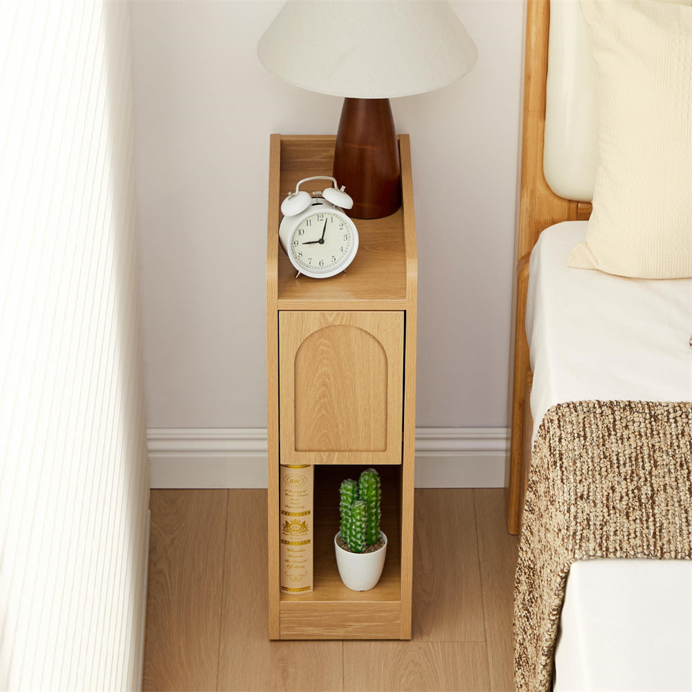 Wooden nightstand with lamp, clock, and books next to a bed