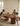 A family of four sits around a large wooden dining table in a bright, modern dining room. The table features a distinctive fluted pedestal base and a rounded organic shape.